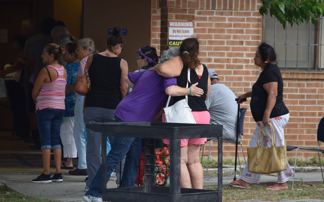 People waiting in line with two women hugging